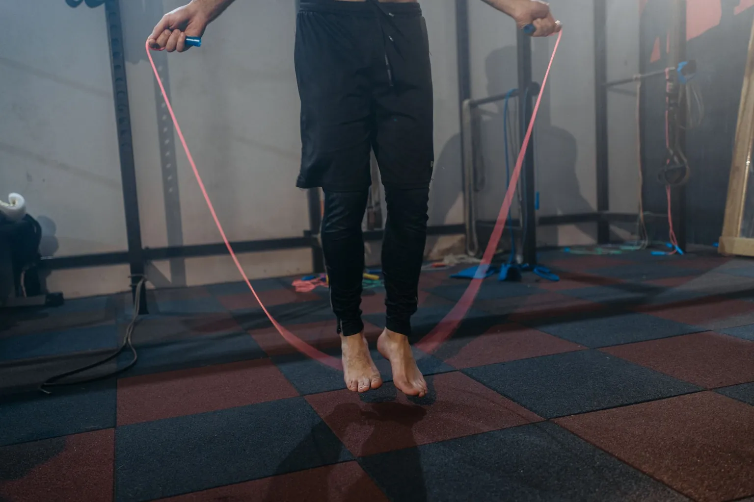 Homme pieds nus sautant à la corde sur le sol amortissant d'une salle de sport